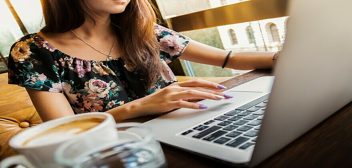 A person sitting at a desk with an open laptop typing.