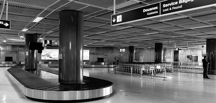 Black and White image of an empty airport baggage collection lounge with empty and stationary luggage conveyor belt