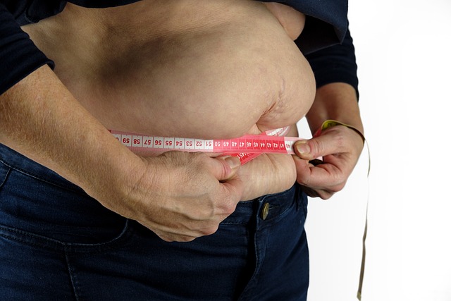 The Image of a flabby Fatty Belly with the owner pinching a tape measure tightly around the fat stomach. The image is to support the article by Future You Success on Burn Fat - Best Exercise to Lose Belly Fat and enforce that if you over exercise you risk producing excess Cortisol, which will store as fat in the abdomen