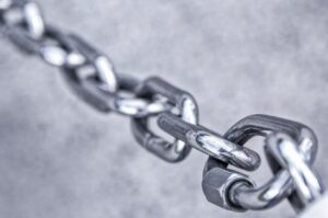 Chrome chain links, linked as a security chain, on a light grey background