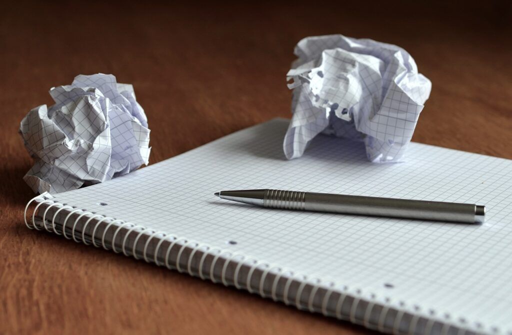 How to Earn Money Through Social Media - a blank notepad and pen with two scrunched up waste pieces of notepaper