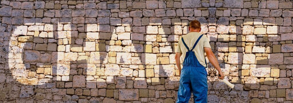 A Decorator painting the word CHANGE on to a Brick Wall