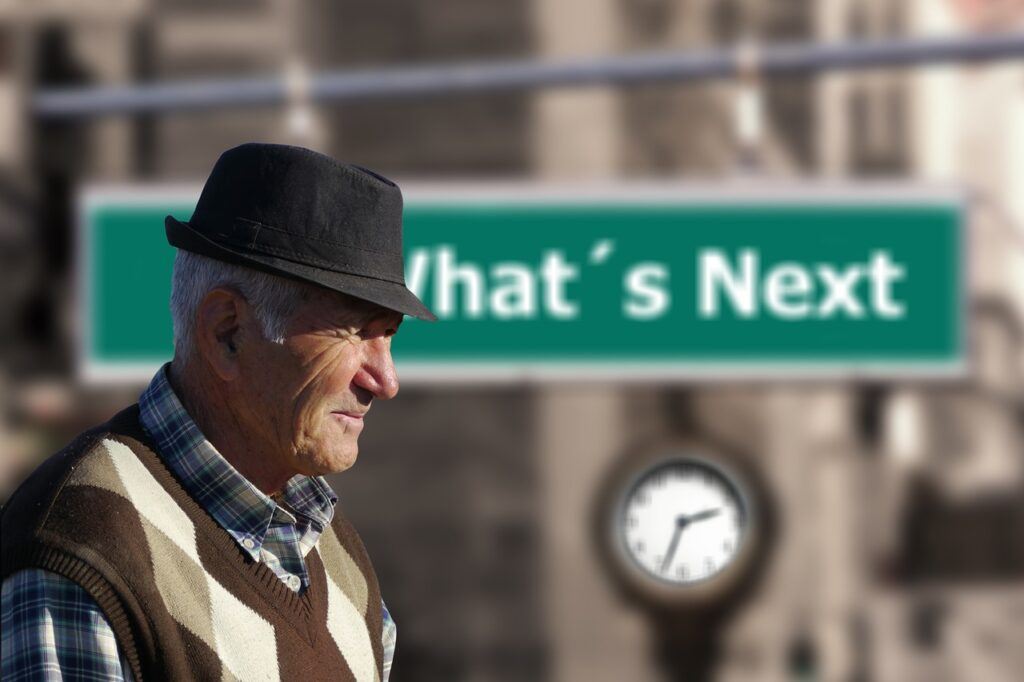 An Old man Sitting in front of a sign saying 'Whats Next' - How to Build Wealth After 50 - Its Never Too Late to Secure Your Financial Future